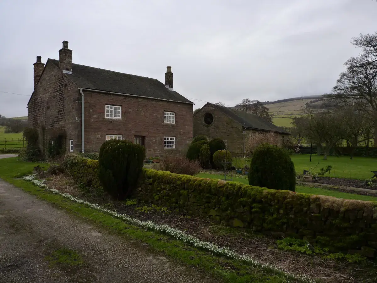 Stone farmhouse and barns with hills behind